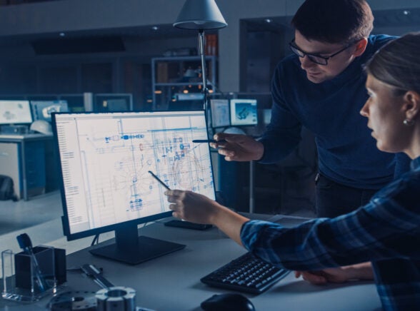 A person shows a colleague something in a project management app on a computer.