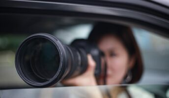 A woman uses a large zoom camera out of a car window